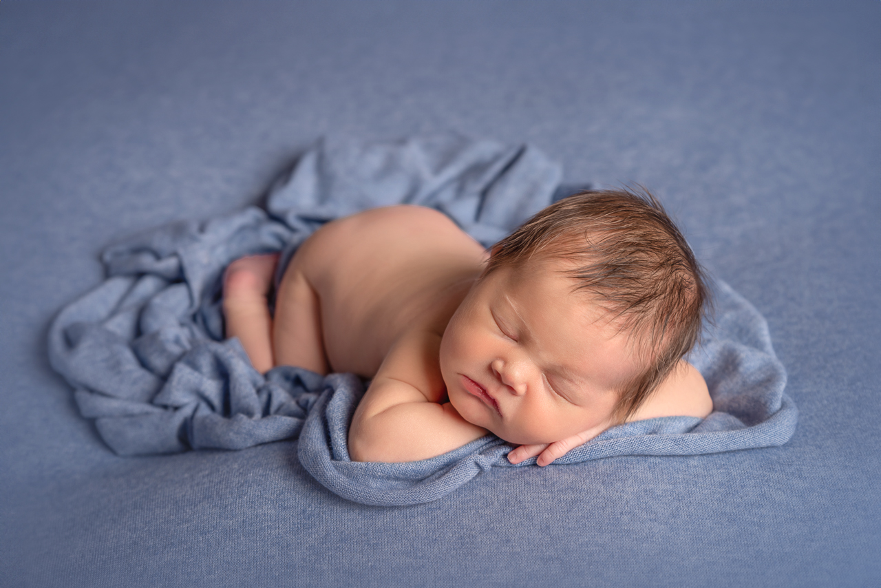 Newborn baby boy sleeping on soft blue blanket during Ogden Utah studio portrait session