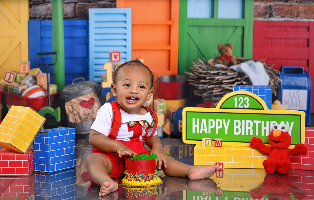 DSC_3917Smash Cake Smash cake photo of baby boy in red suspenders celebrating his first birthday with a colorful block-themed setup at La Bella Sole Photography in North Ogden Utah.
