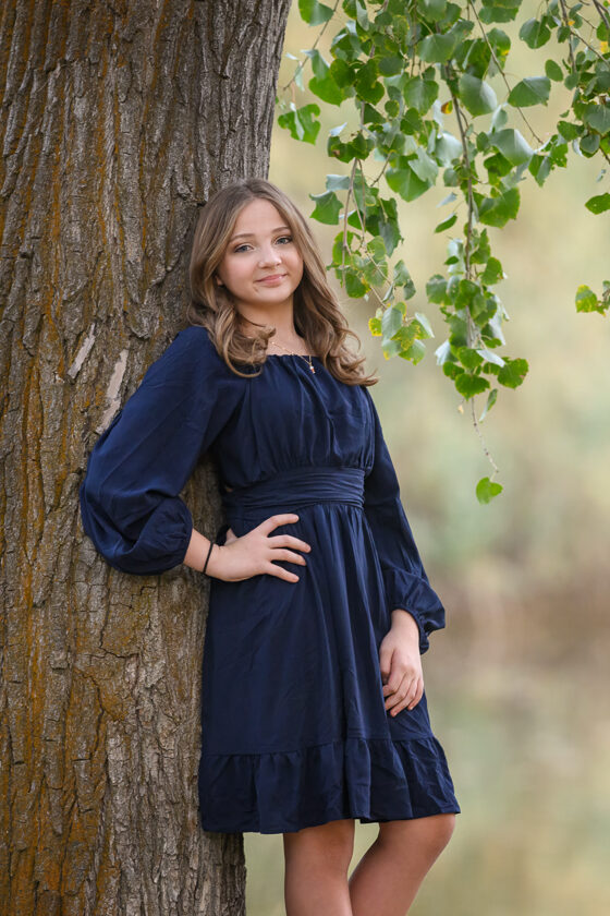 family pictures, outside, teen Teen girl in navy dress posing by a tree during outdoor family portrait session in Ogden Utah